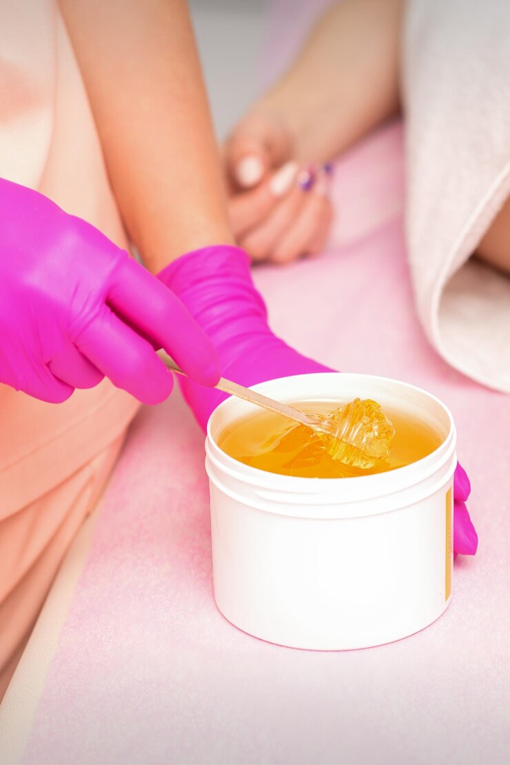 Beautician with a white jar of wax sugaring before hair removal at the spa