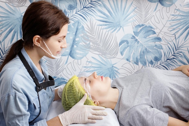 Photo beautician and woman at the reception on the couch skin rejuvenation