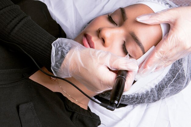 Photo beauticians hands performing permanent eye line make-up