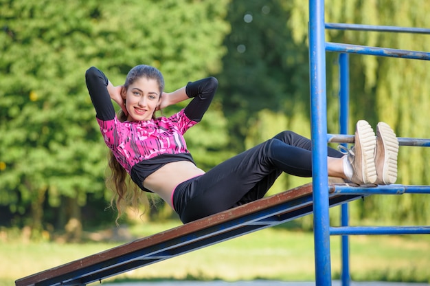 Beautifel girl doing fitness exercises in park. Summer time