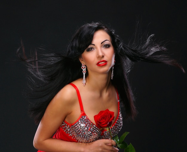 Beautifil young woman with a rose on dark background
