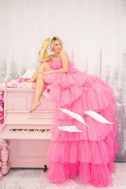 Beautifu lblonde woman posing on pink piano. High quality photo