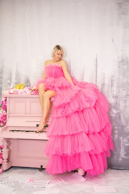 Beautifu lblonde woman posing on pink piano. High quality photo