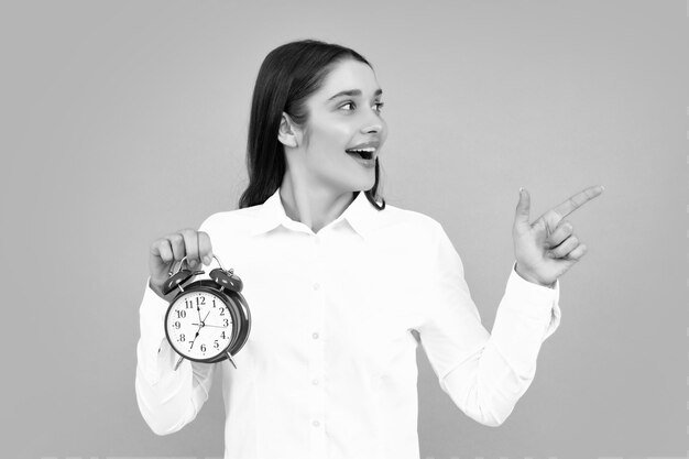 Foto beautifu donne con orologio ritratto di giovane attraente scioccata stupita sorpresa ragazza che tiene l'orologio isolato su sfondo di colore grigio