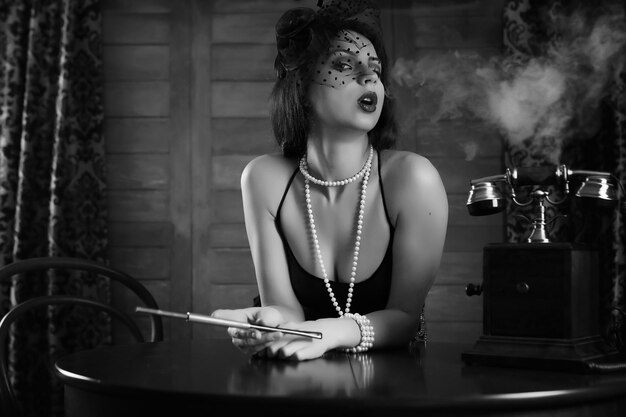 Photo beautiful 1930s girl smokes a cigarette at the table