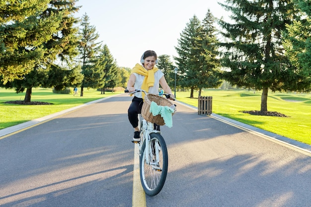 Bella donna matura attiva con la bici sulla strada nel parco