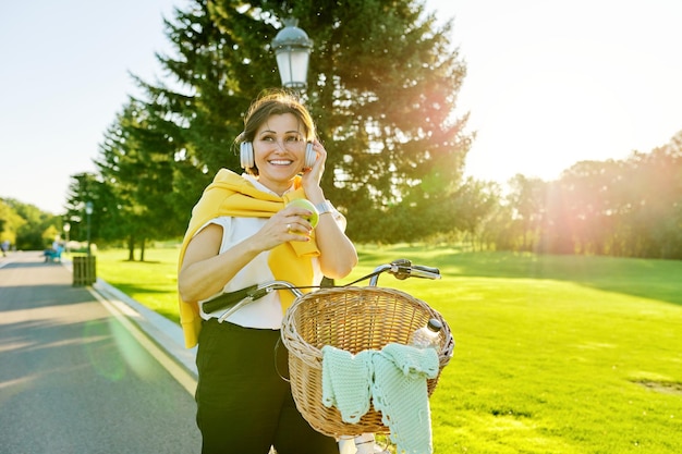 Beautiful active mature woman with bike on the road in the park