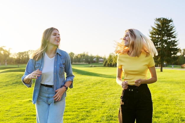 Beautiful active running young women, green lawns of the park at sunset. Youth, happiness, joy, success, positive concept