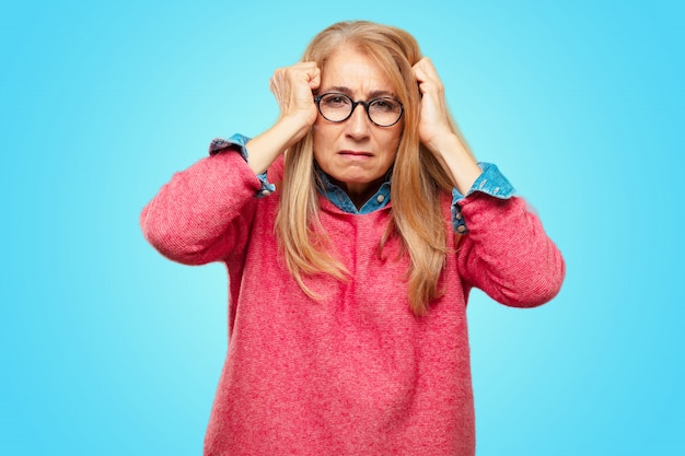 Beautiful adult blonde woman looking stressed and frustrated, looking upwards and holding both hands