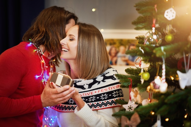 beautiful adult couple with present over Christmas tree