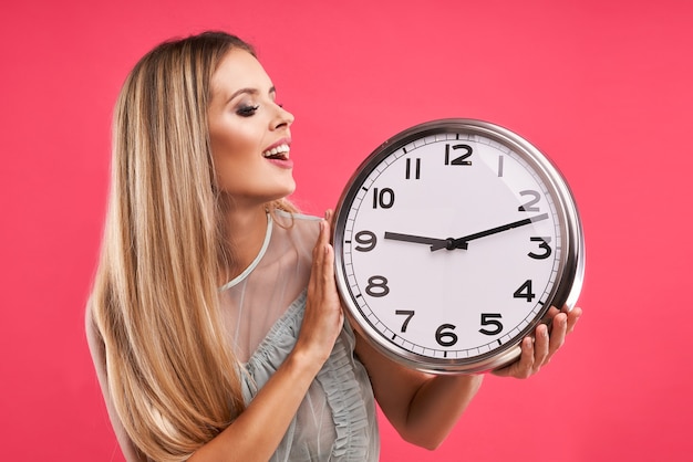 Beautiful adult woman posing over pink with clock