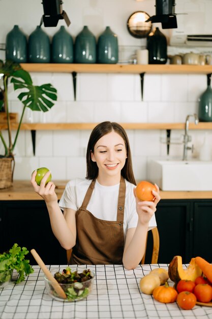 beautiful adult woman with bell peppers looking at camera while making salad at kitche healthy food concept