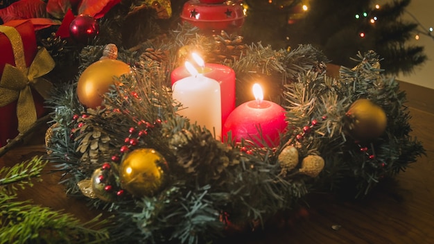 Beautiful Advent wreath with burning candles against decorated Christmas tree