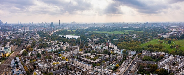 Beautiful aerial view of London with many green parks and city skyscrapers in the foreground.