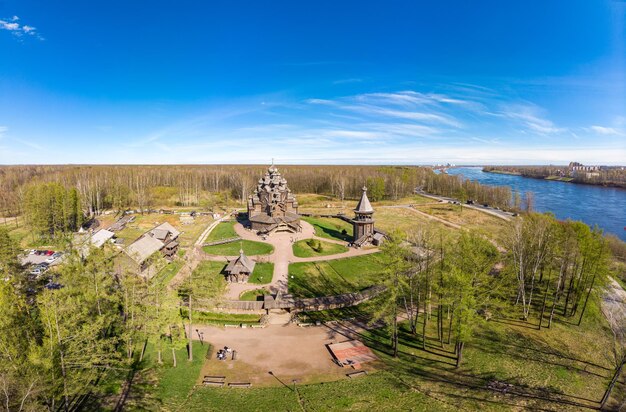 Foto bellissima vista aerea del tradizionale villaggio russo con cappella ortodossa in legno e campanile nel maniero di bogoslovka pokrovskaya chiesa a più cupole della santa vergine nel giorno di pasqua san pietroburgo russia