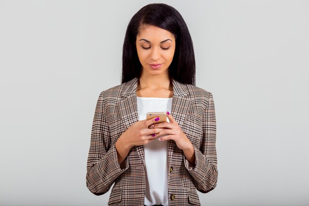 Beautiful African American girl hold the phone in hands on a gray background