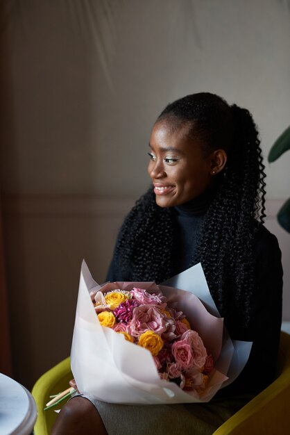 beautiful african american girl holding bouquet of flowers on dating in a cafe