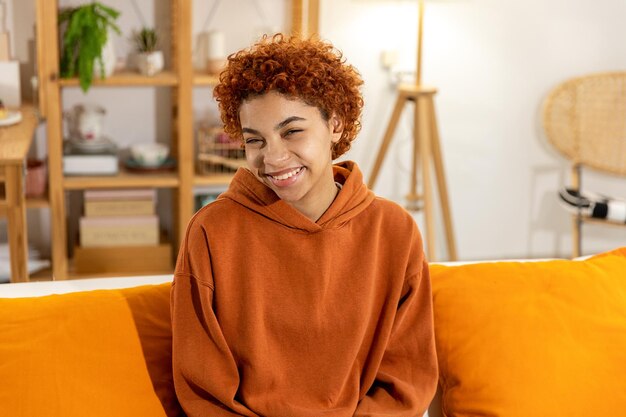 Beautiful african american girl with afro hairstyle smiling sitting on sofa at home indoor young afr