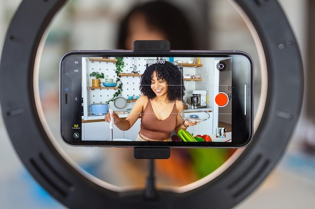 Foto una bella food blogger o vlogger afroamericana che registra un video sullo smartphone