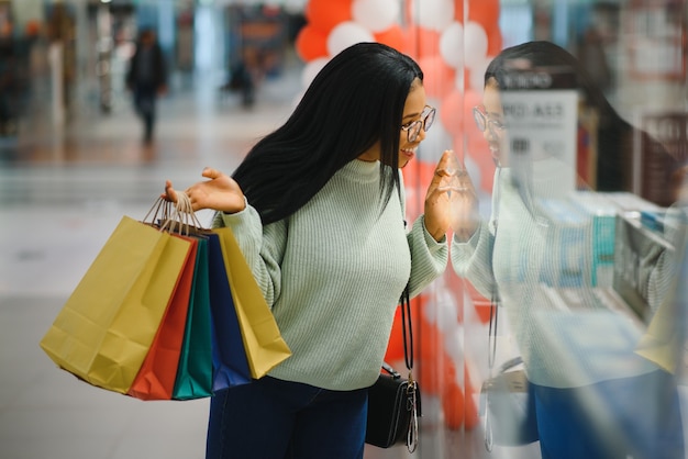 店で色とりどりの買い物袋を持っている美しいアフリカ系アメリカ人の女性。