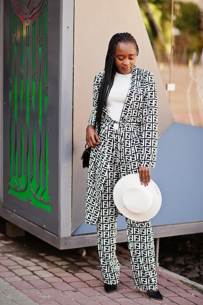 Photo beautiful african american woman natural makeup wear fashion clothes casual black and white dress code office style total blouse and pants suit and hat