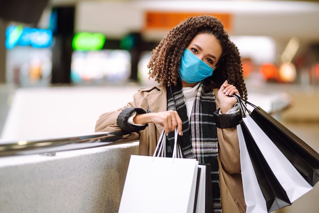 Beautiful african american woman in protective mask after shopping near the store