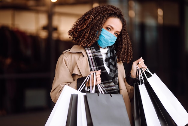 Photo beautiful african american woman in protective mask after shopping near the store