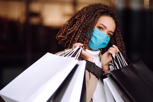 Beautiful african american woman in protective mask after shopping near the store