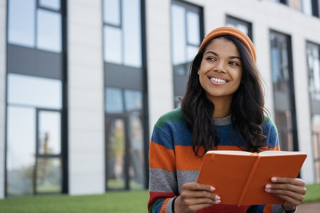 Beautiful African American woman reading book outdoors