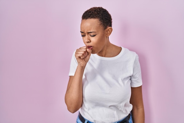 Фото Красивая афроамериканка, стоящая на розовом фоне, чувствует себя плохо и кашляет как симптом простуды или бронхита. концепция здравоохранения.
