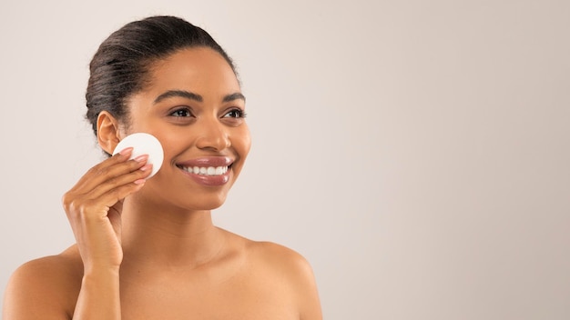 Beautiful african american woman using facial toner copy space