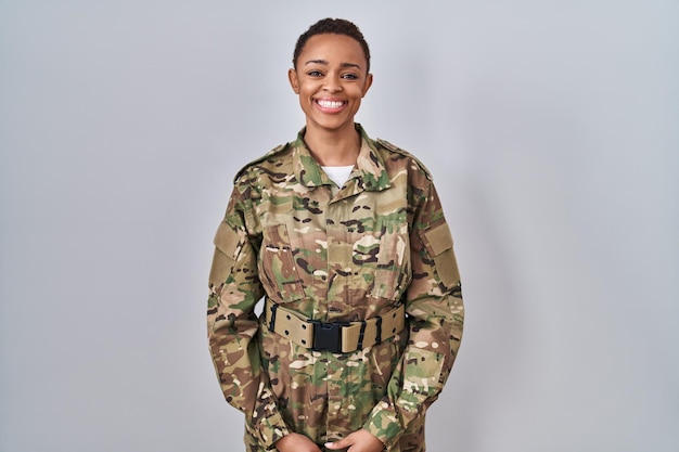 カモフラージュの軍服を着た美しいアフリカ系アメリカ人女性で、幸せでクールな笑顔を顔に浮かべています。幸運な人。