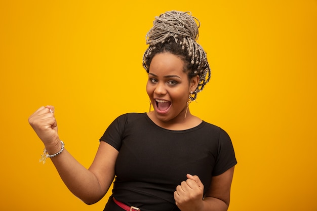 Beautiful african american young woman over isolated yellow excited for success with arms raised celebrating victory smiling. Beautiful female half-length portrait. Winner concept.