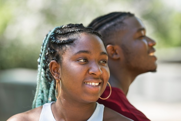 beautiful african couple man and woman sit on a park bench in summer