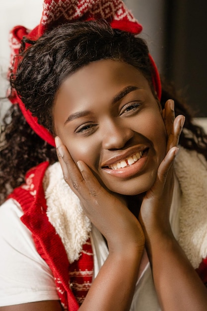 Beautiful african girl model in christmas ornament clothes smiles broadly for camera afro beauty fac...