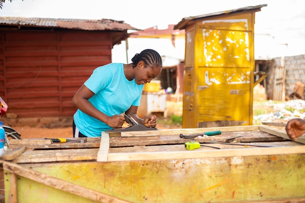 Beautiful african lady smiles as she uses jack plane to dress timber down into size