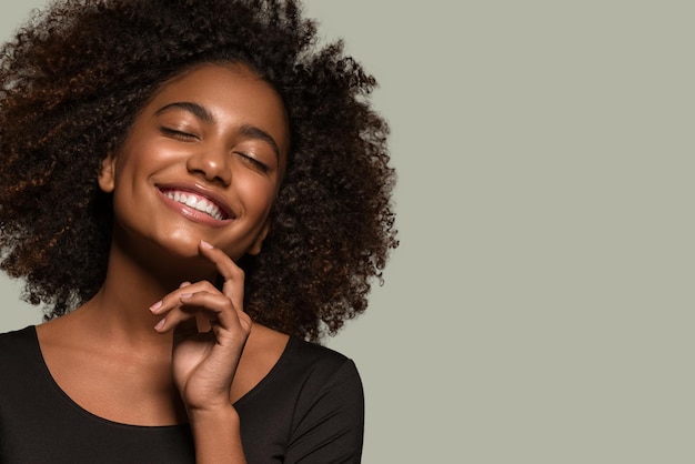 Beautiful african woman black t-shirt portrait afro haircut touching her face Color background green