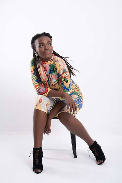 Beautiful African woman hair dreadlocks with a happy posture wearing a flower-patterned dress.