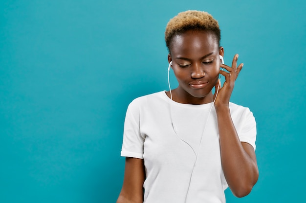 Beautiful african woman listening music with headphones.