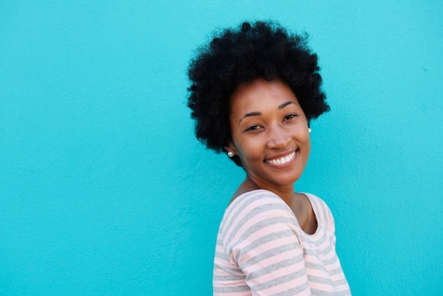 Beautiful african woman smiling against blue wall