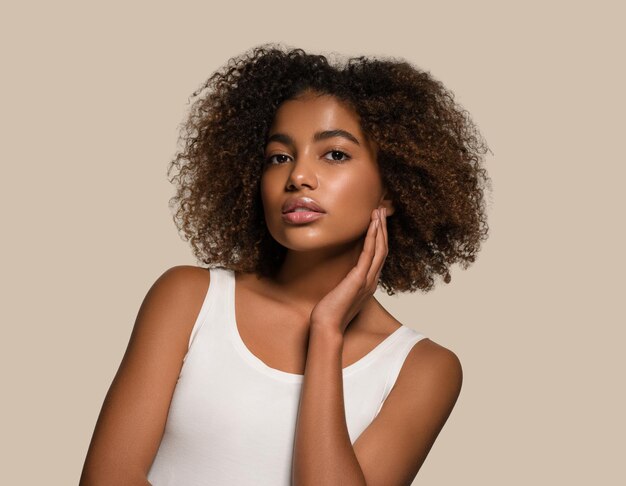 Bella donna africana bianca t-shirt ritratto taglio di capelli afro toccando il viso colore sfondo marrone