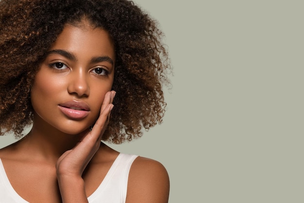 Beautiful african woman white t-shirt portrait afro haircut touching her face Color background green