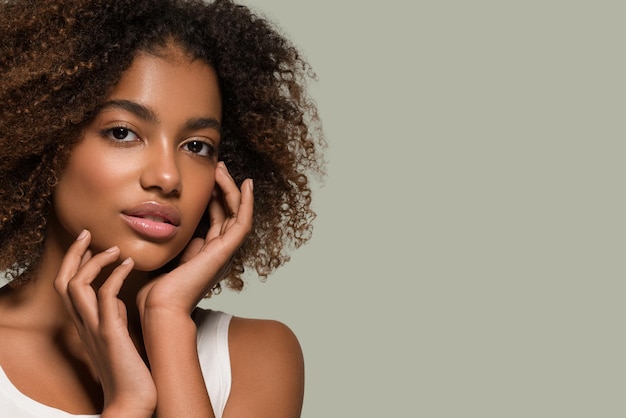 Photo beautiful african woman white t-shirt portrait afro haircut touching her face color background green