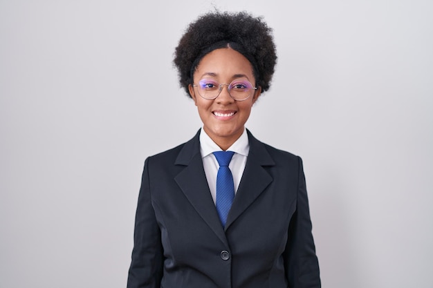 Beautiful african woman with curly hair wearing business jacket and glasses with a happy and cool smile on face. lucky person.