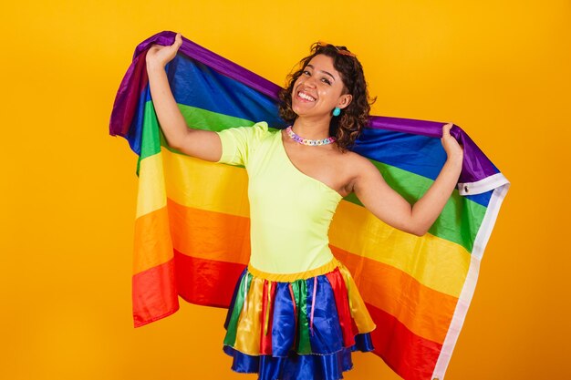 Beautiful afro american brazilian woman in carnival clothes holding lgbt flag gay pride