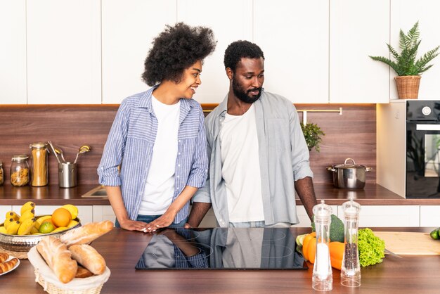 Beautiful afro american couple cooking at home - Beautiful and cheerful black couple preparing dinner together in the kitchen