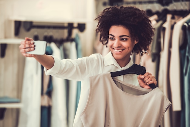 Beautiful Afro American girl is choosing clothes.