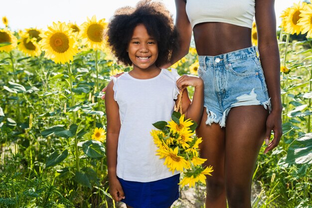 Beautiful afroamerican mom and daughter palying and having fun in a sunflowers field