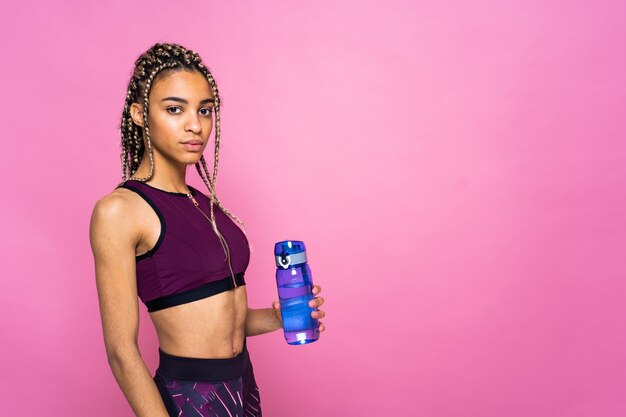 Beautiful afroamerican woman with pigtails portrait on colored wall doing sport exercises