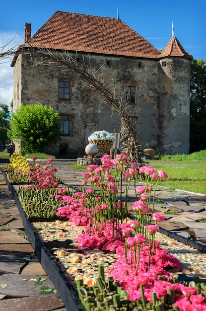 Beautiful alley in the park with a floral arrangement of roses near the ancient castle